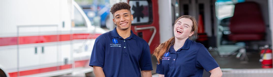 两个护理专业的学生微笑地站在一辆救护车前